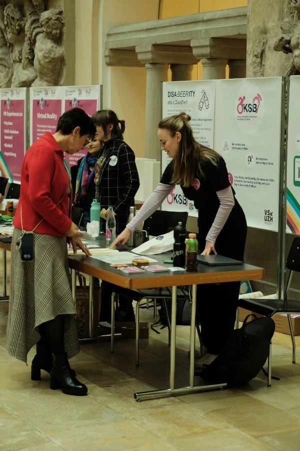 Infostand KSB/VSUZH: Die Prorektorin Lehre und Studium, Gabriele Siegert, steht am Infostand von KSB/VSUZH mit Flyern und Informationsmaterial zum Thema Behinderung im Lichthof der UZH.